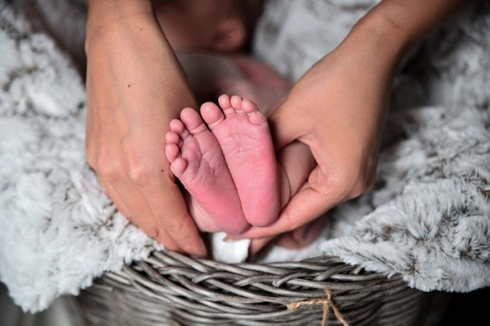 Füsse eines Neugeborenen mit Mutters Händen